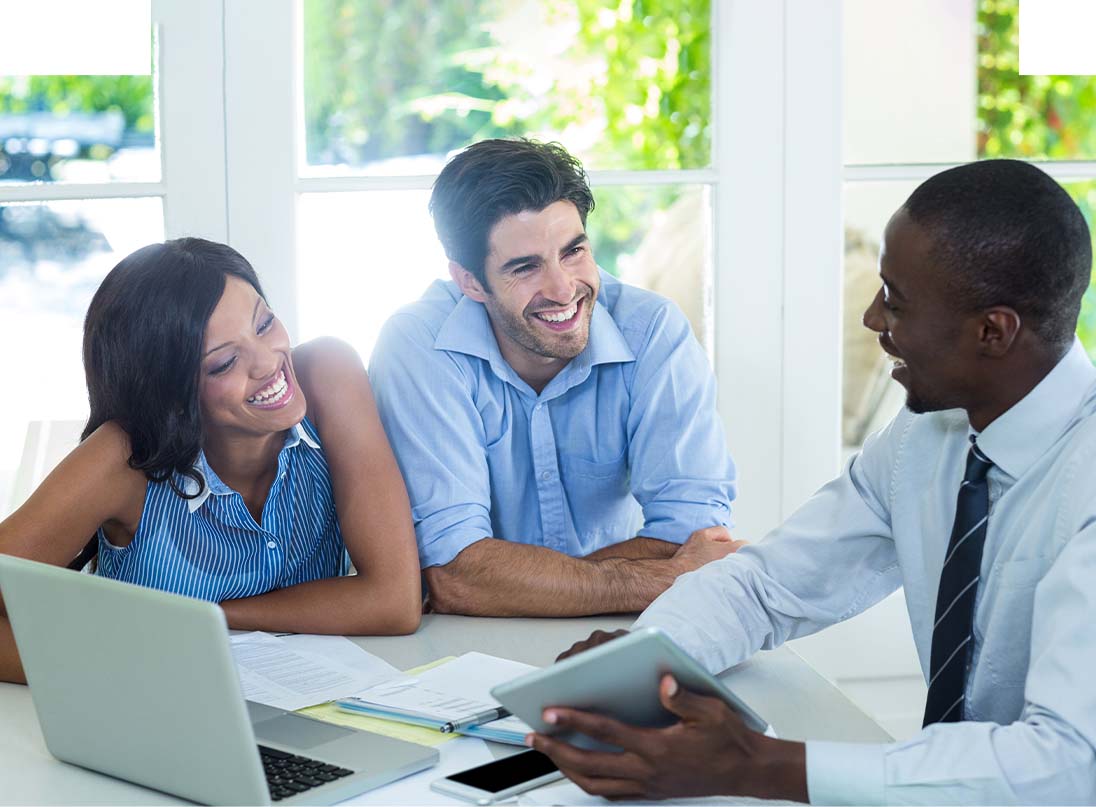 three people talking at a table with a laptop
